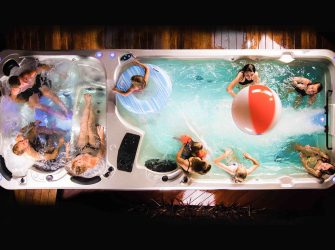 People playing with a beach ball and doughnut ring in swim spa